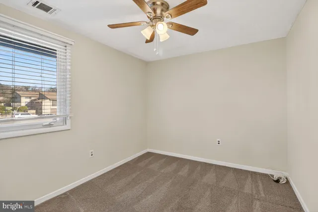 an empty room with a window and a fan