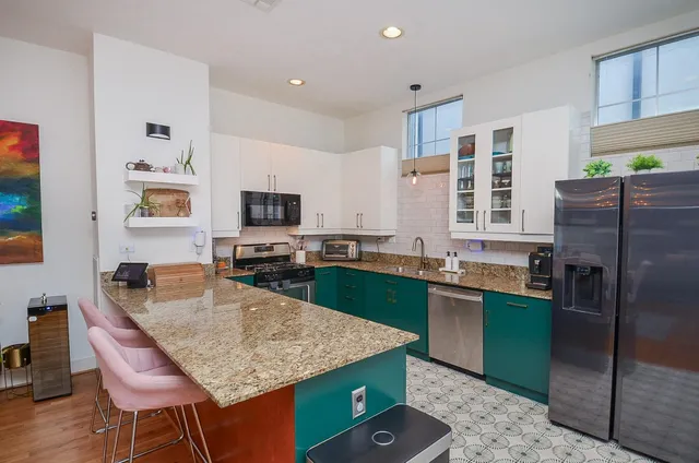 a kitchen with granite countertop kitchen island stainless steel appliances a refrigerator sink and stove