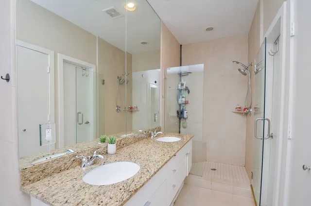 a bathroom with a granite countertop sink a mirror and a shower