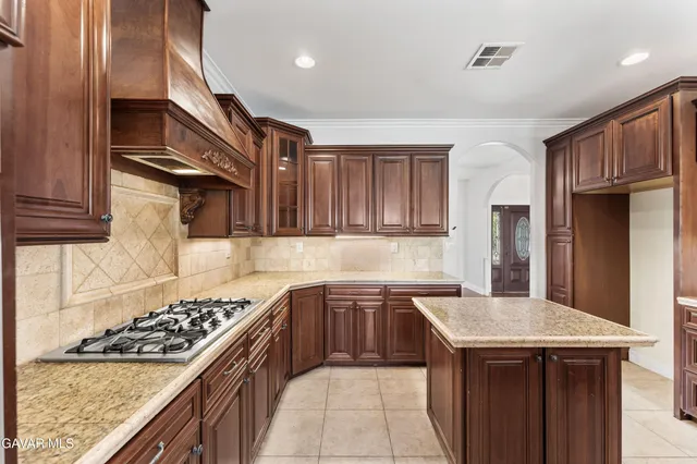 a room with stainless steel appliances kitchen island granite countertop a stove a sink and a refrigerator