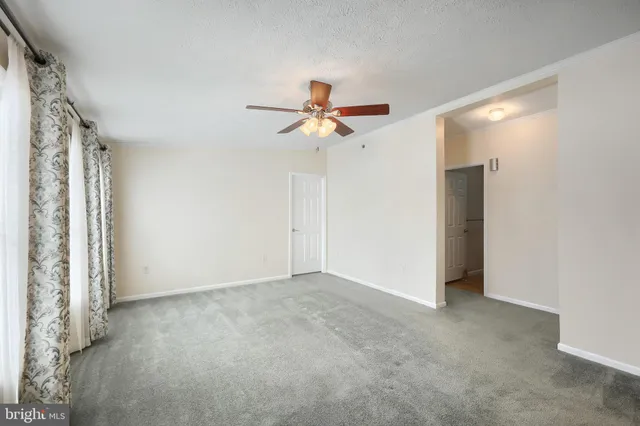 a view of a room with a ceiling fan and window