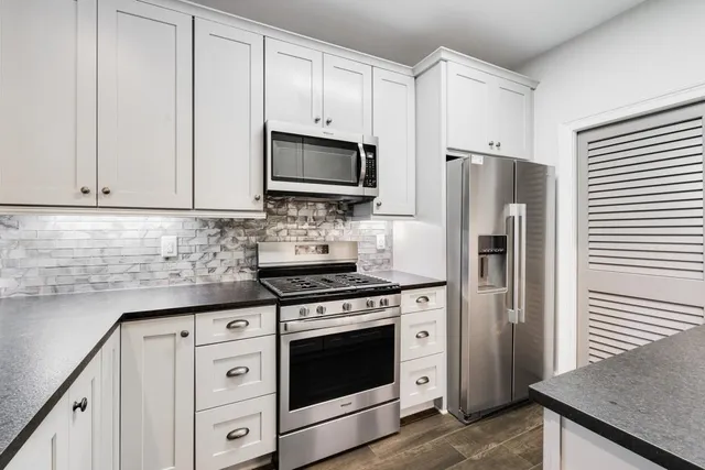 a kitchen with white cabinets and stainless steel appliances