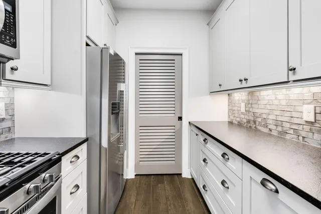 a kitchen with granite countertop white cabinets and white appliances