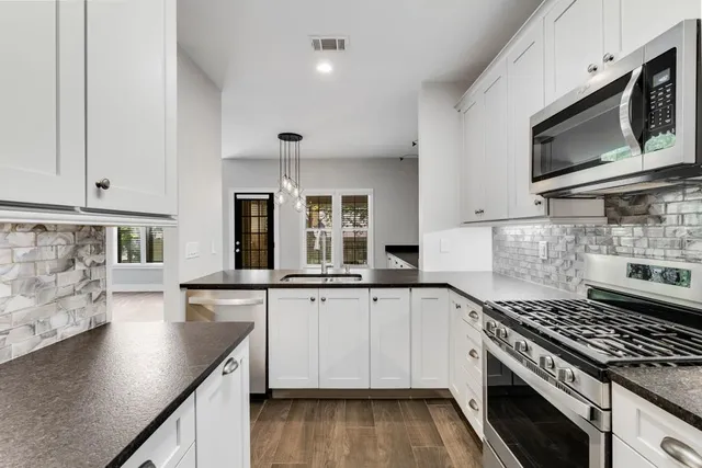 a kitchen with stainless steel appliances granite countertop a stove a sink and a microwave