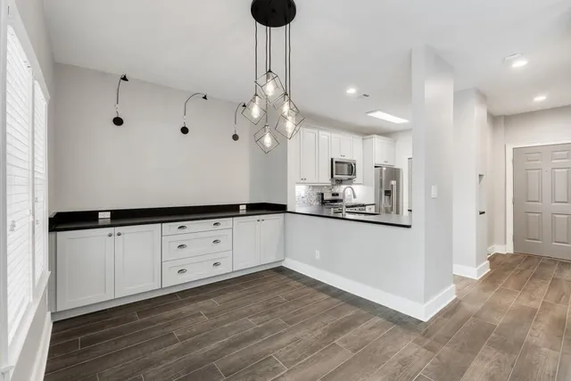 a kitchen with granite countertop white cabinets and refrigerator