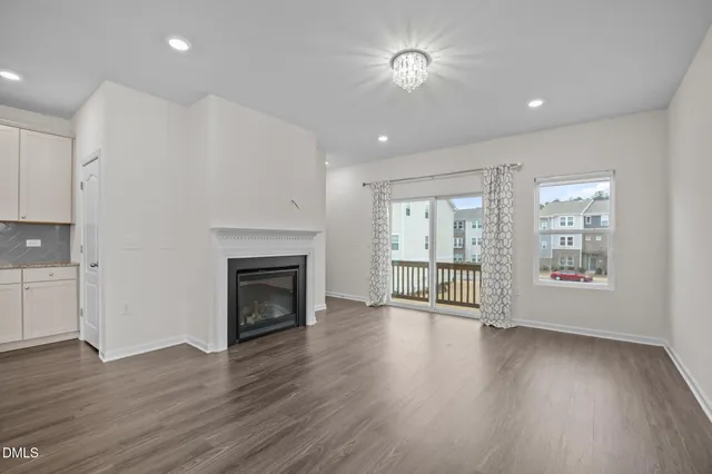 a view of an empty room with wooden floor fireplace and a window