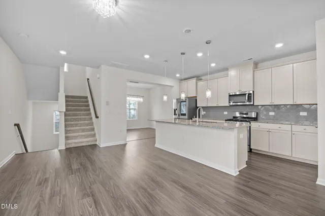 a kitchen with wooden floors white cabinets and stainless steel appliances