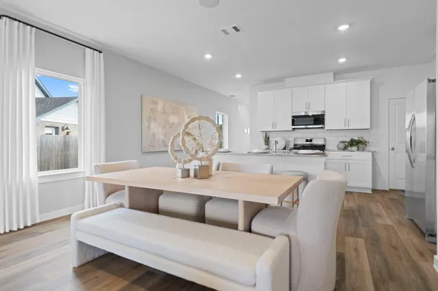 a living room with stainless steel appliances kitchen island granite countertop a sink a stove a dining table and chairs