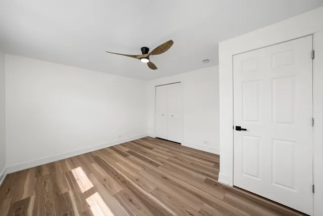 a view of empty room with wooden floor and ceiling fan