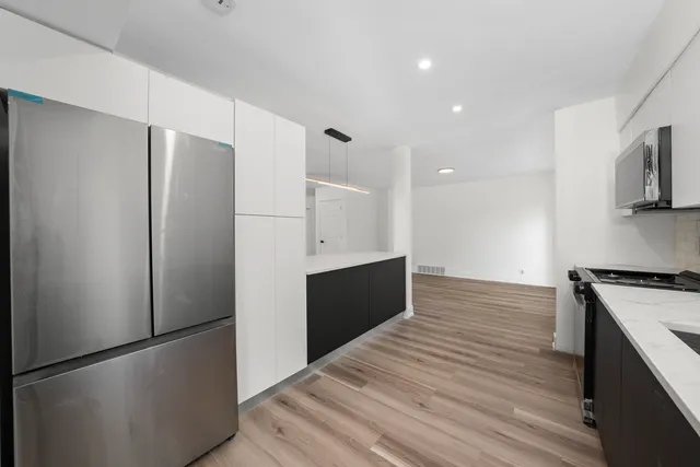 a kitchen with stainless steel appliances granite countertop a refrigerator a stove and a microwave with wooden floor