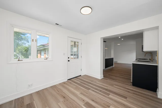 a view of kitchen and empty room with wooden floor