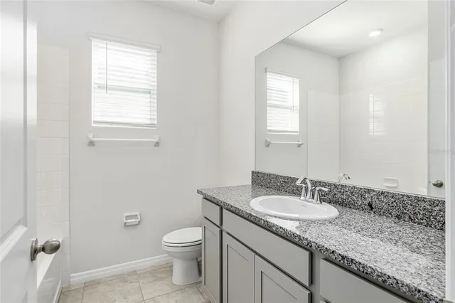 a bathroom with a granite countertop sink a toilet and a mirror