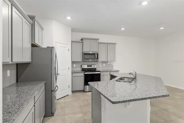 a kitchen with stainless steel appliances granite countertop a kitchen island a stove a refrigerator a sink a microwave and cabinets