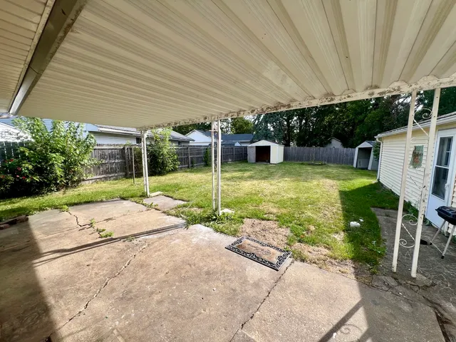 a view of a backyard with table and chairs under an umbrella
