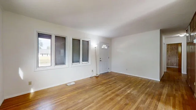 a view of an empty room with wooden floor and a window