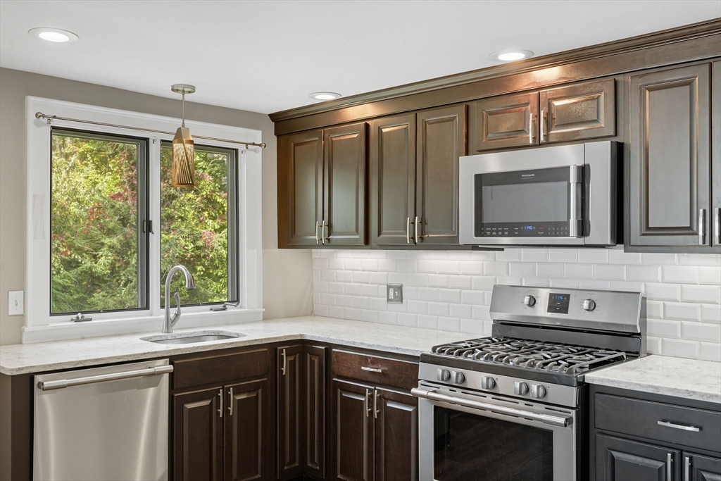 116 Hartwick Street Springfield, MA 01108 - Photo 18 of 38 a kitchen with granite countertop a stove top oven cabinetry a sink and a window