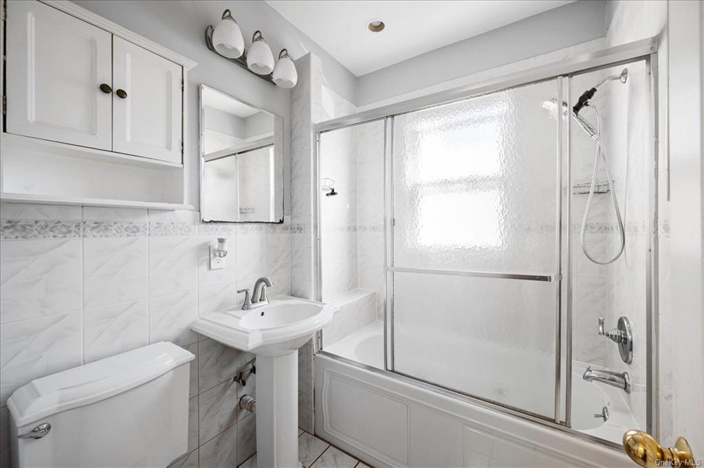 1076 Rhinelander Avenue Bronx, NY 10461 - Photo 22 of 31 a bathroom with a sink a mirror a toilet and shower