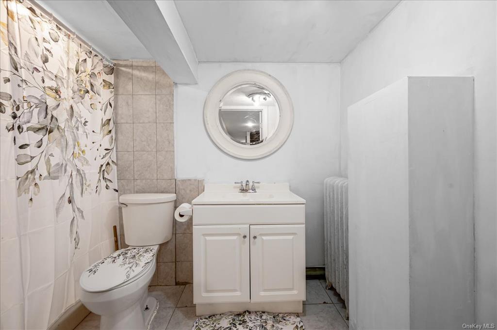 1076 Rhinelander Avenue Bronx, NY 10461 - Photo 23 of 31 a bathroom with a toilet a sink and a mirror