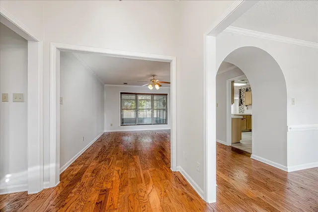 a view of a hallway with wooden floor and a bathroom
