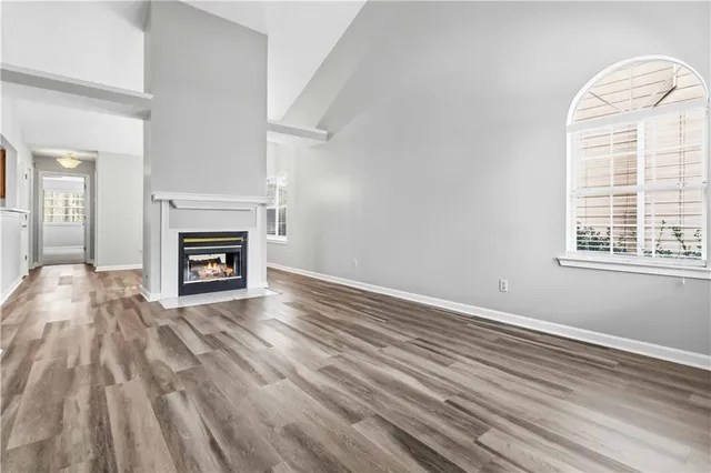 an empty room with wooden floor a fireplace and windows
