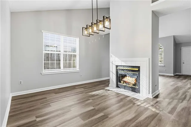 a view of an empty room with wooden floor fireplace and a window