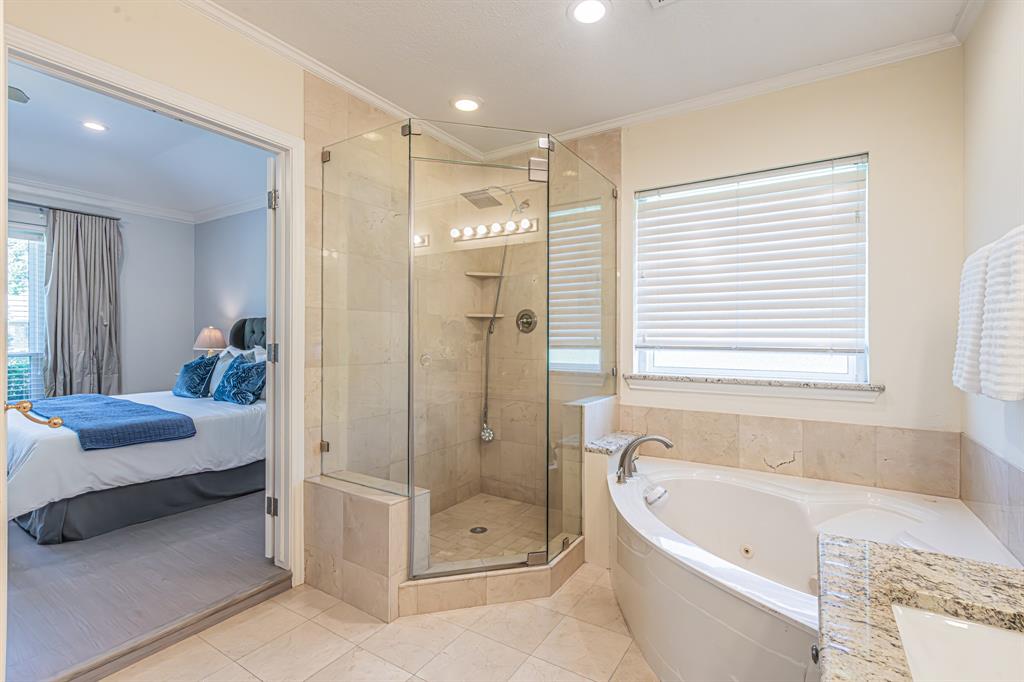 300 Sundance Circle Irving, TX 75063 - Photo 15 of 39 Tiled bathroom featuring a glass-enclosed shower, corner soaking tub, and a window with blinds