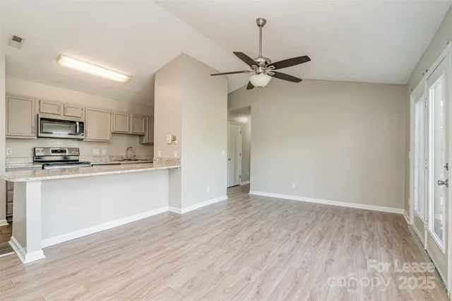 a view of a kitchen with a sink a ceiling fan and wooden floor