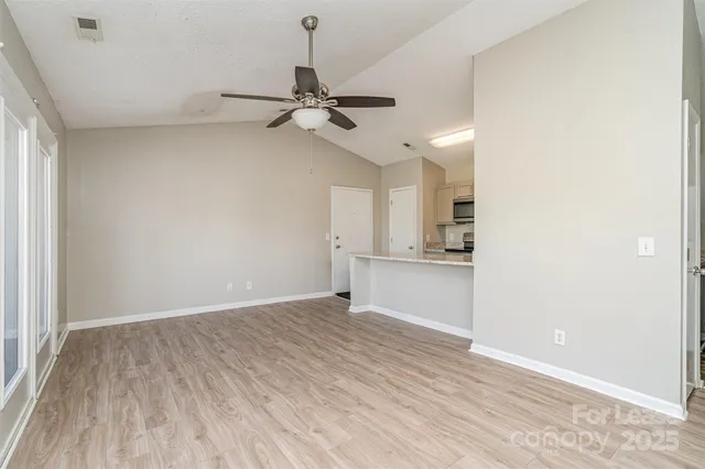 a view of an empty room and window and wooden floor