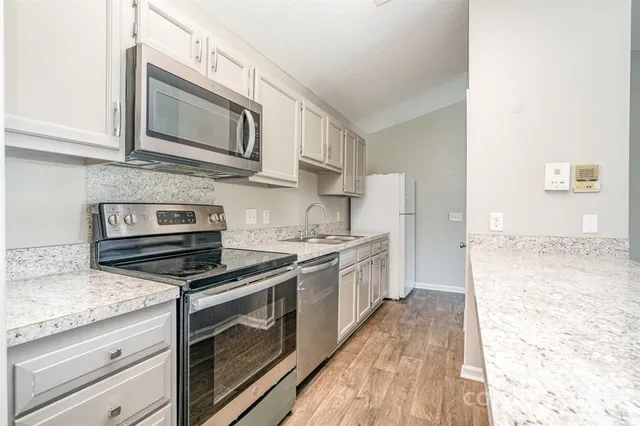 a kitchen with stainless steel appliances granite countertop a stove microwave and sink