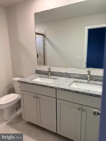 a bathroom with a granite countertop sink a toilet and a mirror