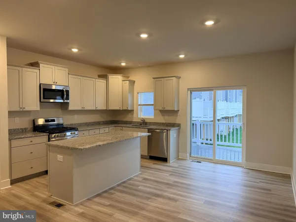 a large kitchen with stainless steel appliances granite countertop a stove a sink and a refrigerator