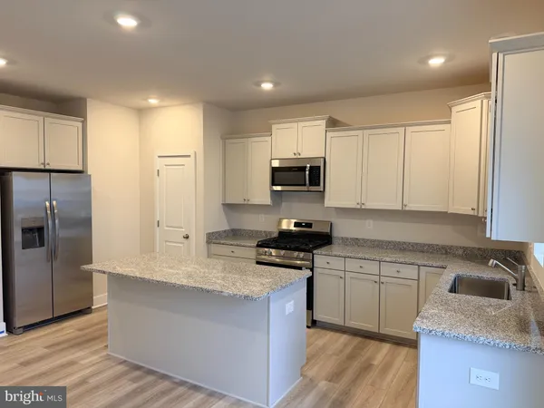 a kitchen with kitchen island granite countertop a sink a counter top space stainless steel appliances and cabinets