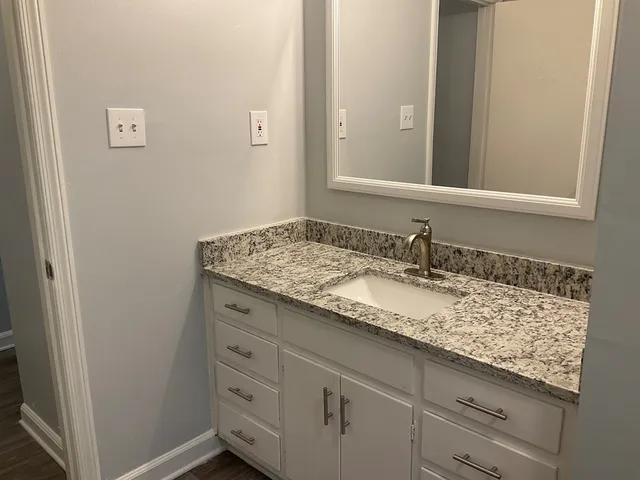a bathroom with a granite countertop sink and a mirror