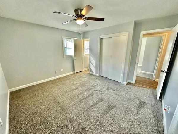 an empty room with windows and fan