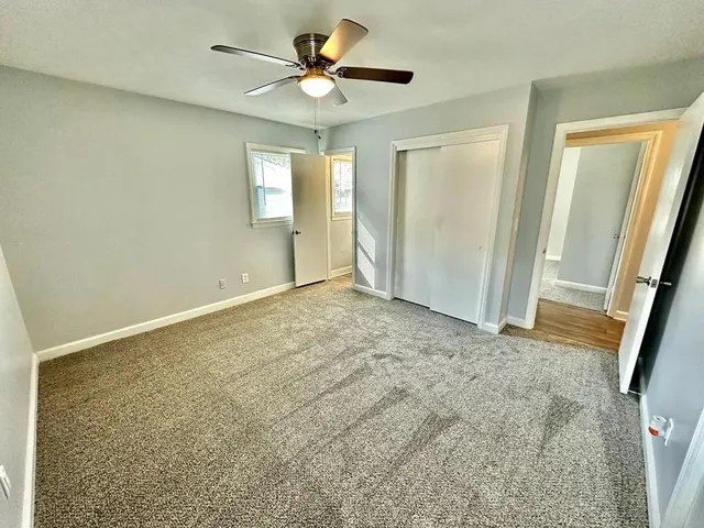 an empty room with windows and fan