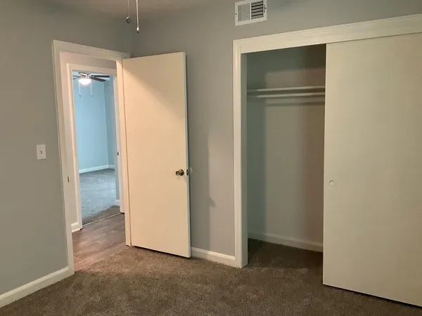 a view of an empty room with closet and wooden floor