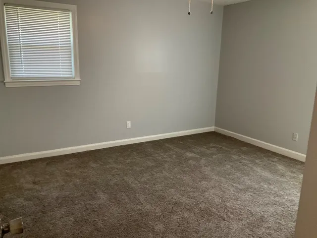 a view of an empty room with closet and a window