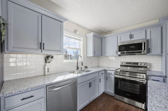 a kitchen with stainless steel appliances granite countertop a sink a stove a microwave and wooden cabinets