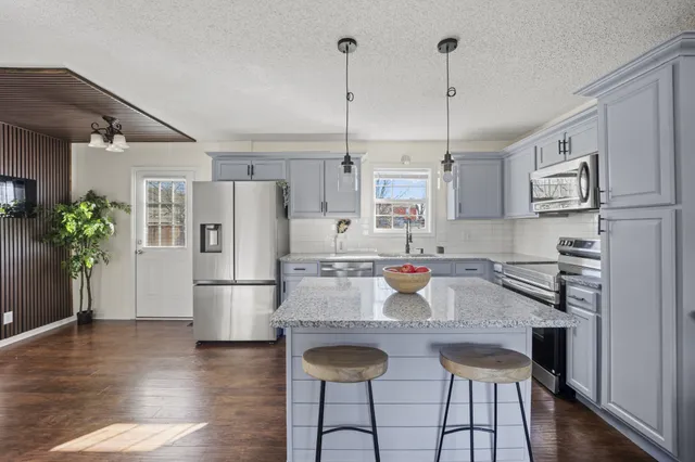 a kitchen with stainless steel appliances granite countertop a refrigerator and a stove top oven