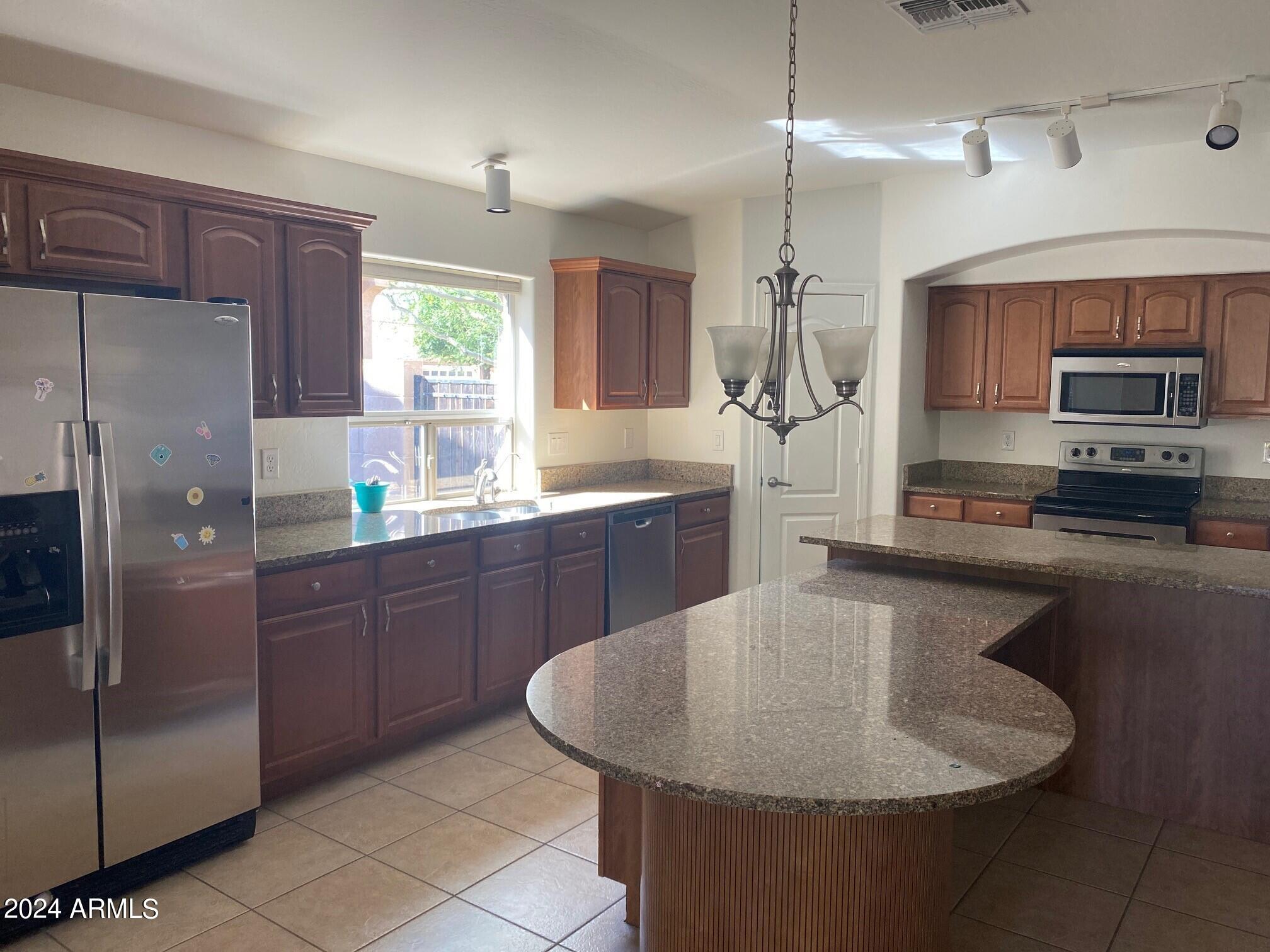 2812 East Questa Drive Phoenix, AZ 85024 - Photo 9 of 32 a kitchen with stainless steel appliances granite countertop a sink a microwave a refrigerator and wooden cabinets