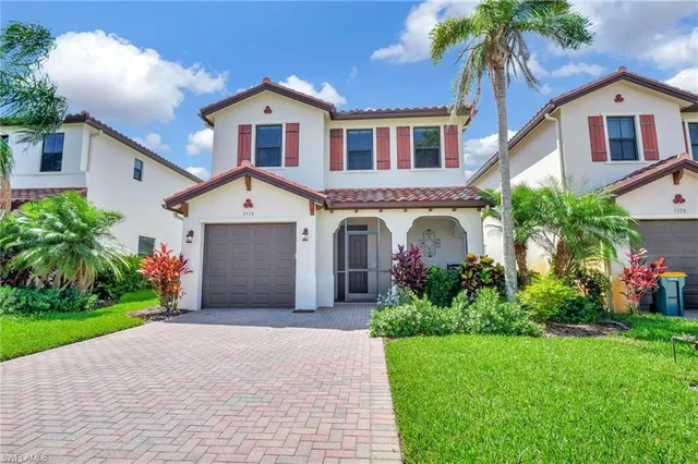 a front view of a house with a garden and palm trees