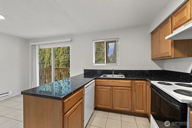 a kitchen with granite countertop a sink stove and cabinets