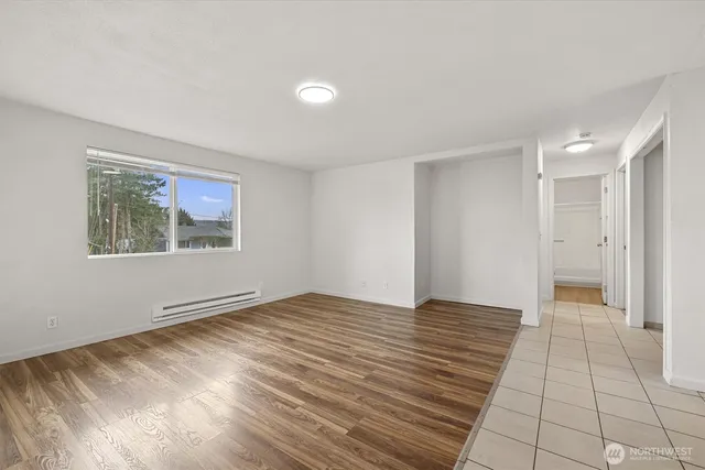 a view of an empty room with wooden floor and a window