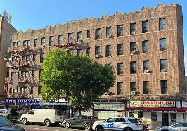 a front view of a building with lot of cars and trees