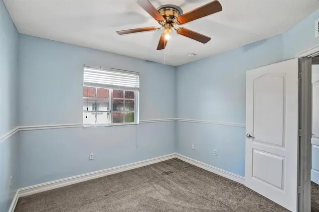 an empty room with a window and a fan
