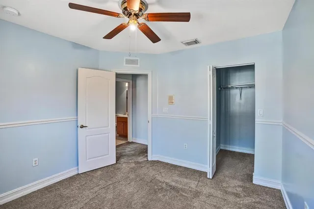 an empty room with closet and a chandelier fan