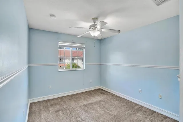 an empty room with a window and ceiling fan