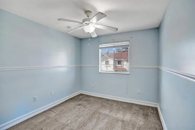an empty room with wooden floor and fan