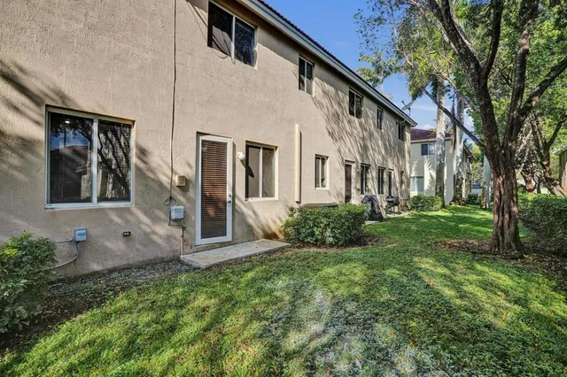 a view of a white house with a big yard and large tree