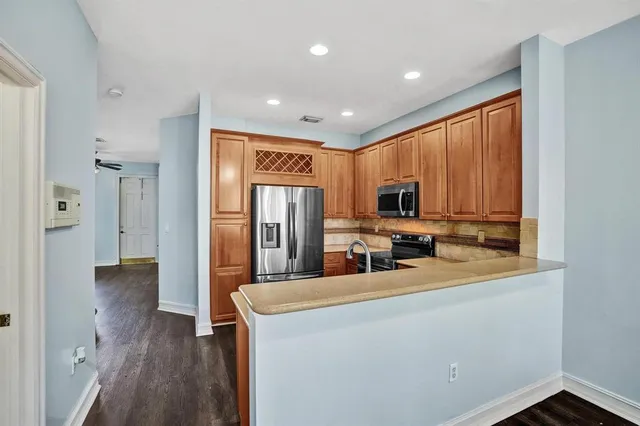a kitchen with stainless steel appliances a refrigerator sink and wooden floor